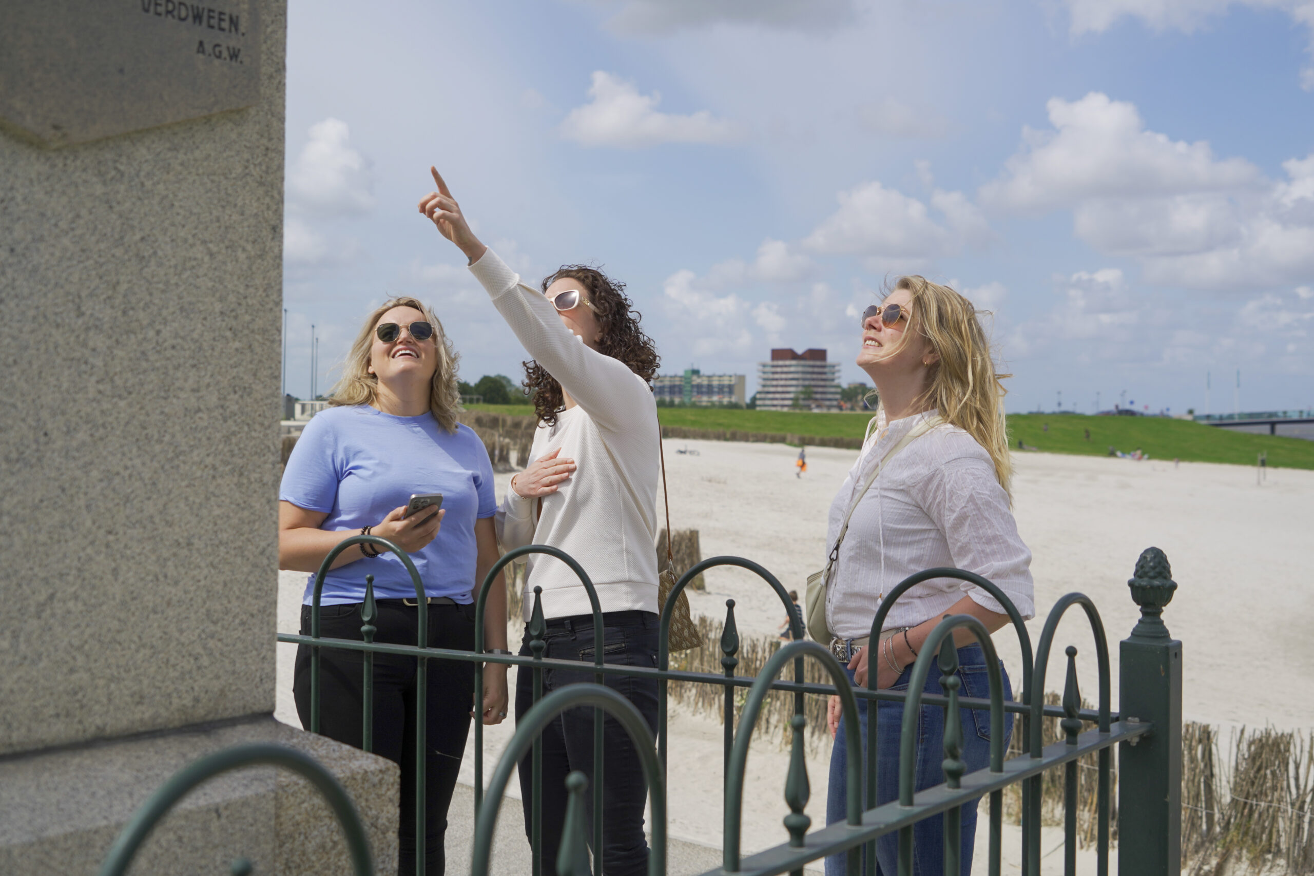 3 vrouwen staan bij het strand van Delfzijl. een wijst omhoog. 